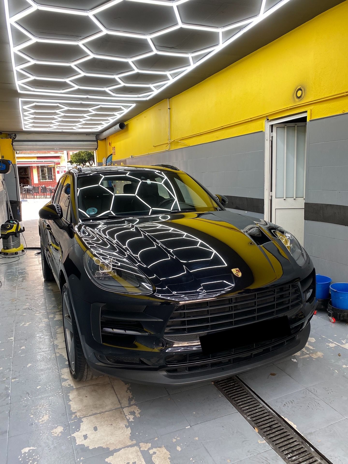 Porsche Macan negro en el estudio con el techo hexagonal reflejado en el capó — limpieza de motor en San Pedro de Alcántara